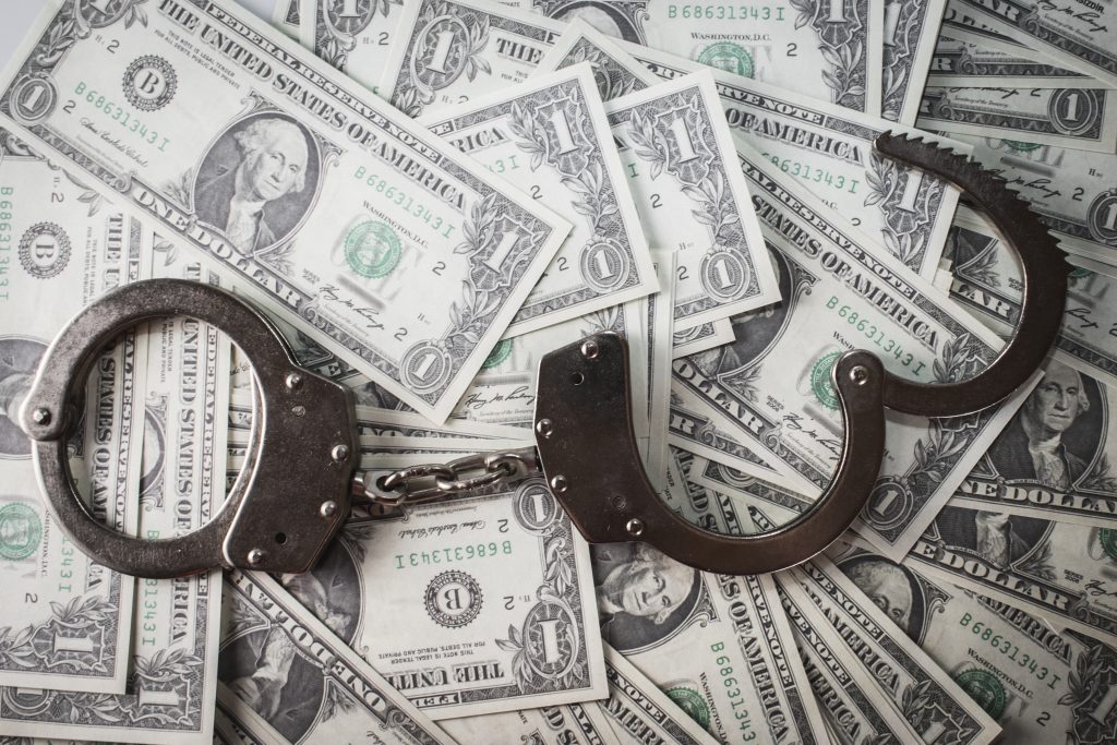 Closeup shot of metal handcuffs and dollars-money-laundering